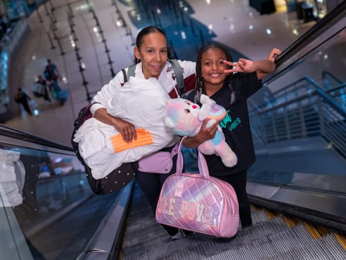 Mother and child riding escalator with overnight gear
