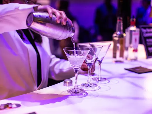 Martini glasses being filled by bartender