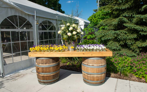 Outdoor barrel table with rows of flowers in vases