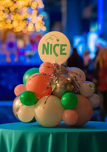 Table with holiday centerpiece of clustered ornaments and "Nice" sign