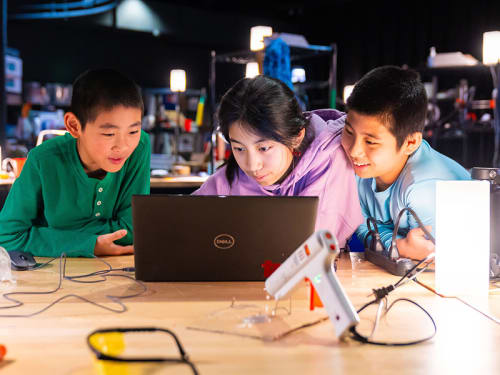 Three campers gathered around a Fab Lab laptop