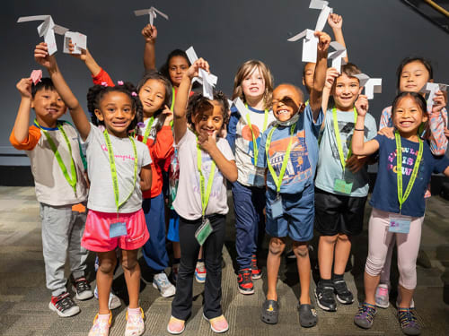 Young campers showing off their paper airplanes