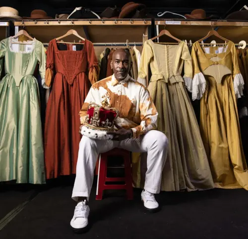 Paul Tazewell seated before a display of his costumes
