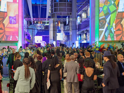 2025 Gala attendees in Rotunda below two large artwork projections