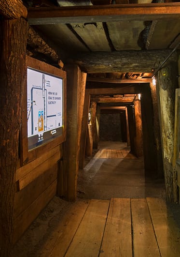 Wooden corridor tunnel with a lit diagram of coal mining process