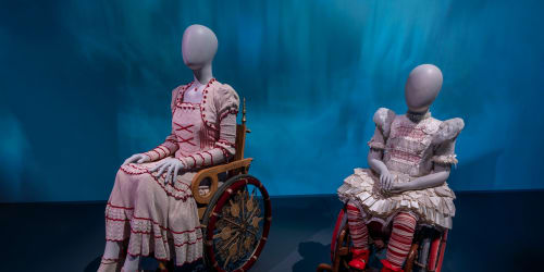 Two mannequins sit in wheelchairs, donning the costume of Nessa and Young Nessa from the film adaptation of 'Wicked'.