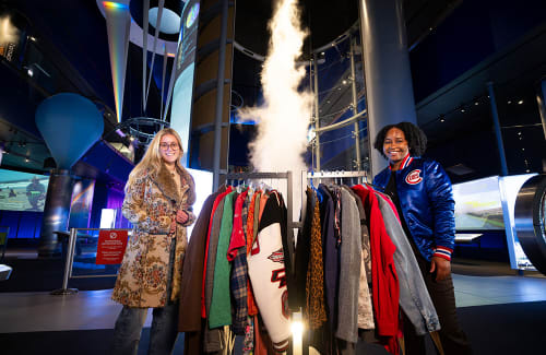 Two women with racks of vintage clothing in Science Storms exhibit