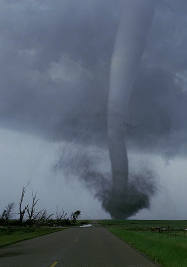 Funnel cloud touching down on landscape in the distance