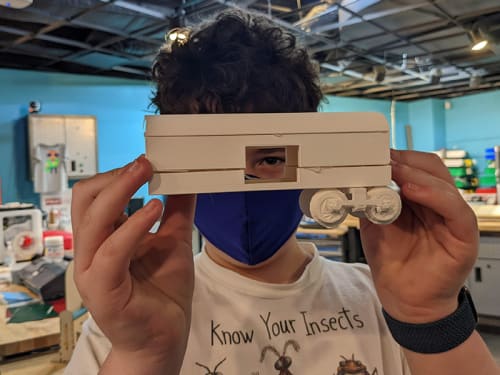 Young person peering through doorway of 3D-printed boxcar's door