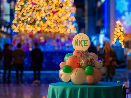 Table with holiday centerpiece of clustered ornaments and "Nice" sign
