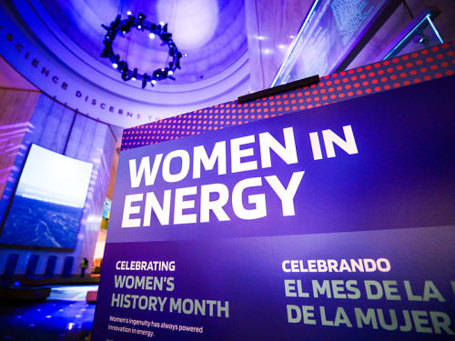 Sign titled "Women in Energy" in foreground of view of Museum Rotunda
