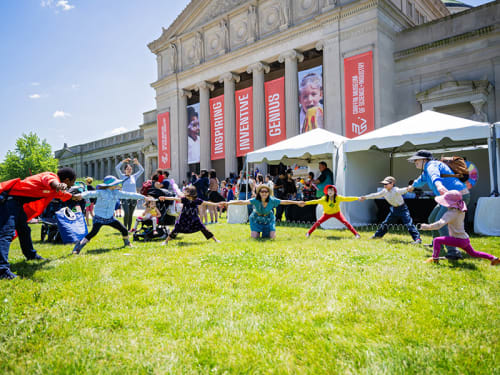 Group holding hands in a circle game on the Museum front lawn
