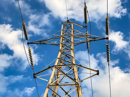 Electric line tower against a blue sky with clouds