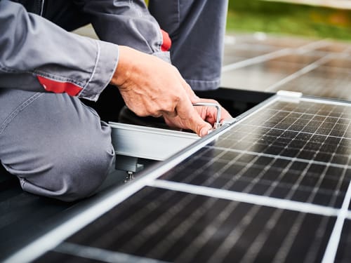 Solar power grid being installed by worker with a wrench