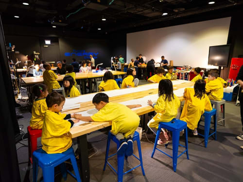 A group of children in matching t-shirts gather around a table for an activity at a Griffin MSI camp.