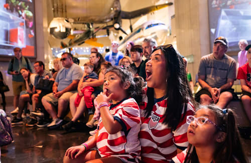 Museum guests seated in Rotunda watching with animated reactions