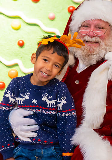 Children with antler headbands posing with Santa Claus