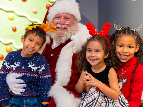 Children with antler headbands posing with Santa Claus