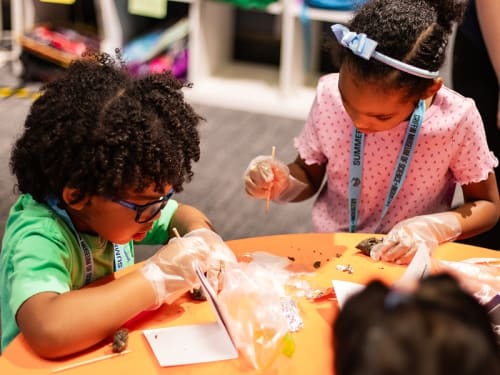 Two children focus on an activity provided by one of Griffin MSI's Curiosity Kits