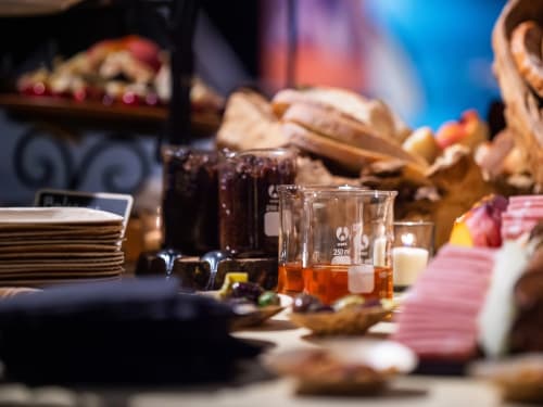 An array of food and beverage displayed including a specialty cocktail served in a beaker.