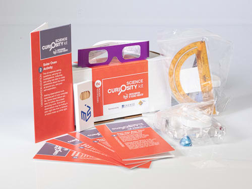 The contents of the "Orange" Science Curiosity Kit are displayed featuring Garden in a Pouch, Map Making, Weather Station, Solar Oven