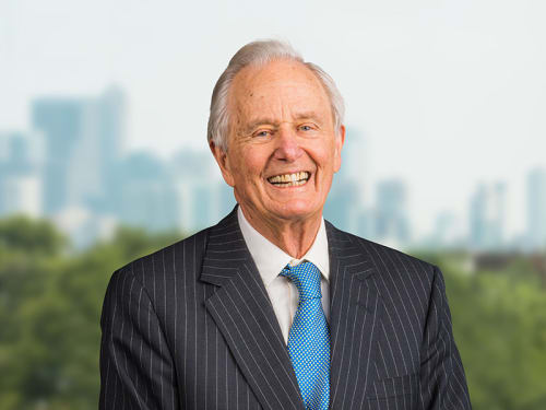 Allan E. Bulley, Jr., a man in a dark suit and blue tie, smiles in front of a Chicago cityscape background