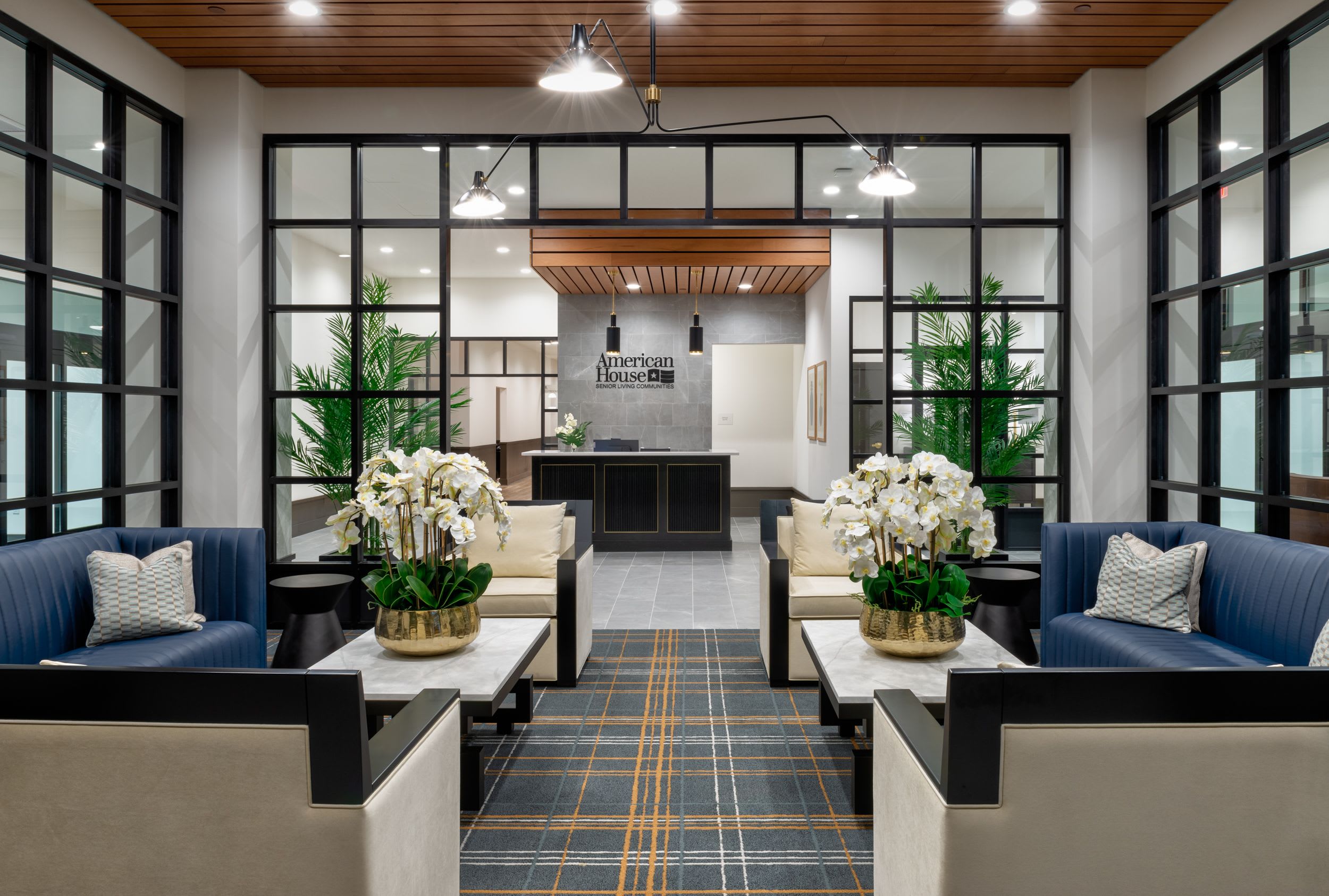 The lobby lounge at American House Oak Park Senior Living with comfortable couches, flowers and bright lighting.