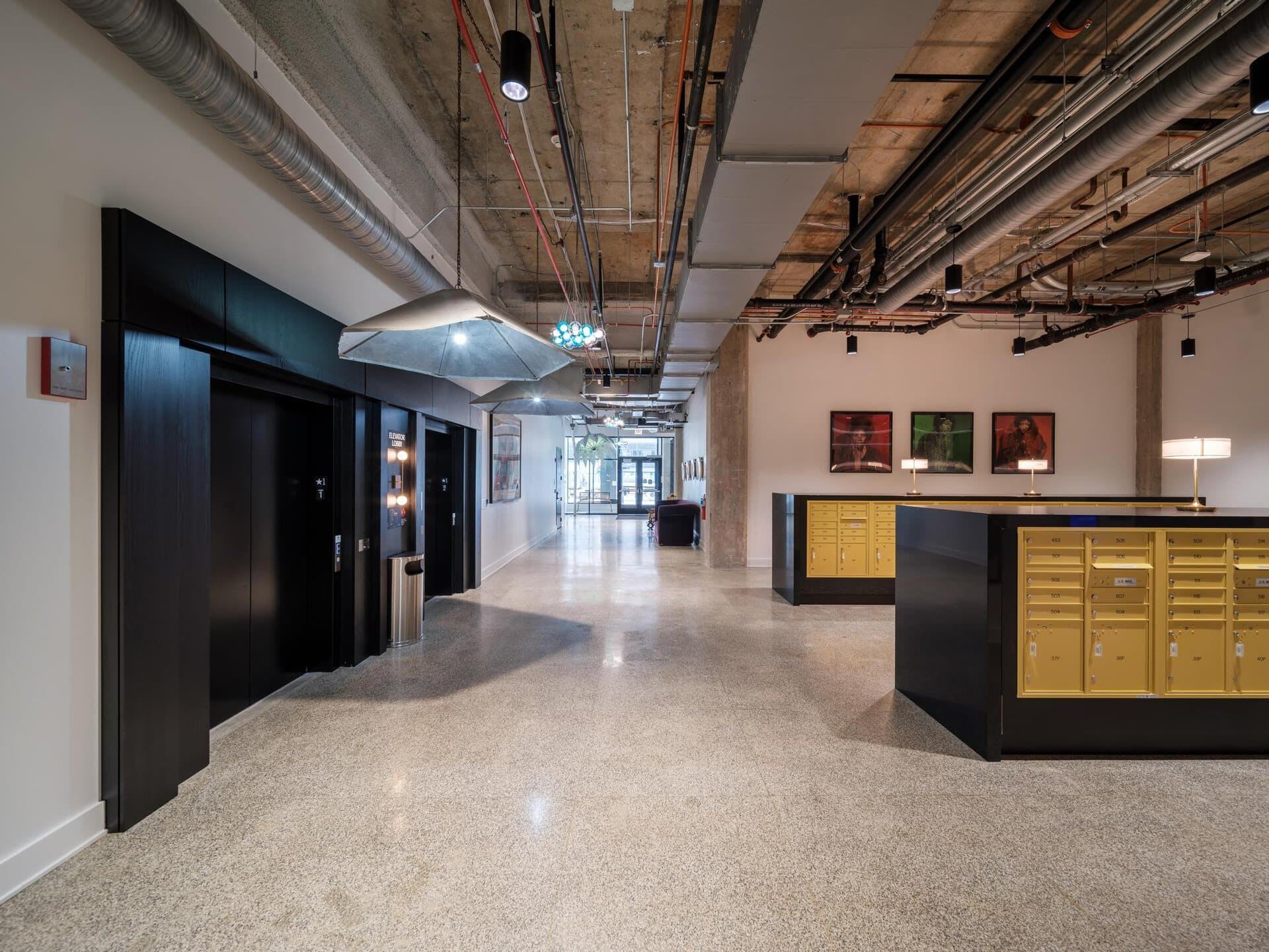 The entrance to Six Corners Redevelopment, with a mailroom, two elevators and some custom-made hanging pendant lights.