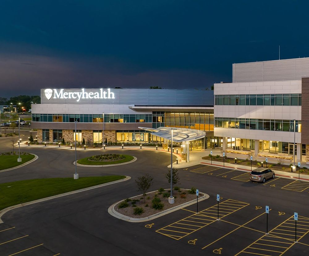 Another view of the exterior of Mercy Health with the inside illuminated.