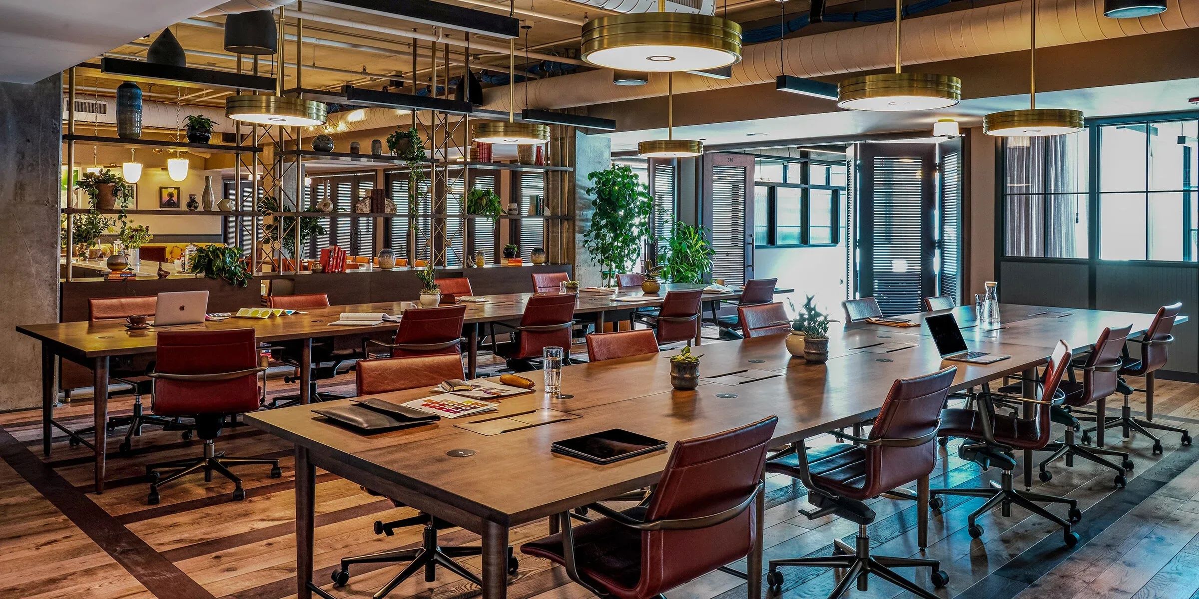 Co-working space with a couple gray couches, tables and natural light coming in from large windows.