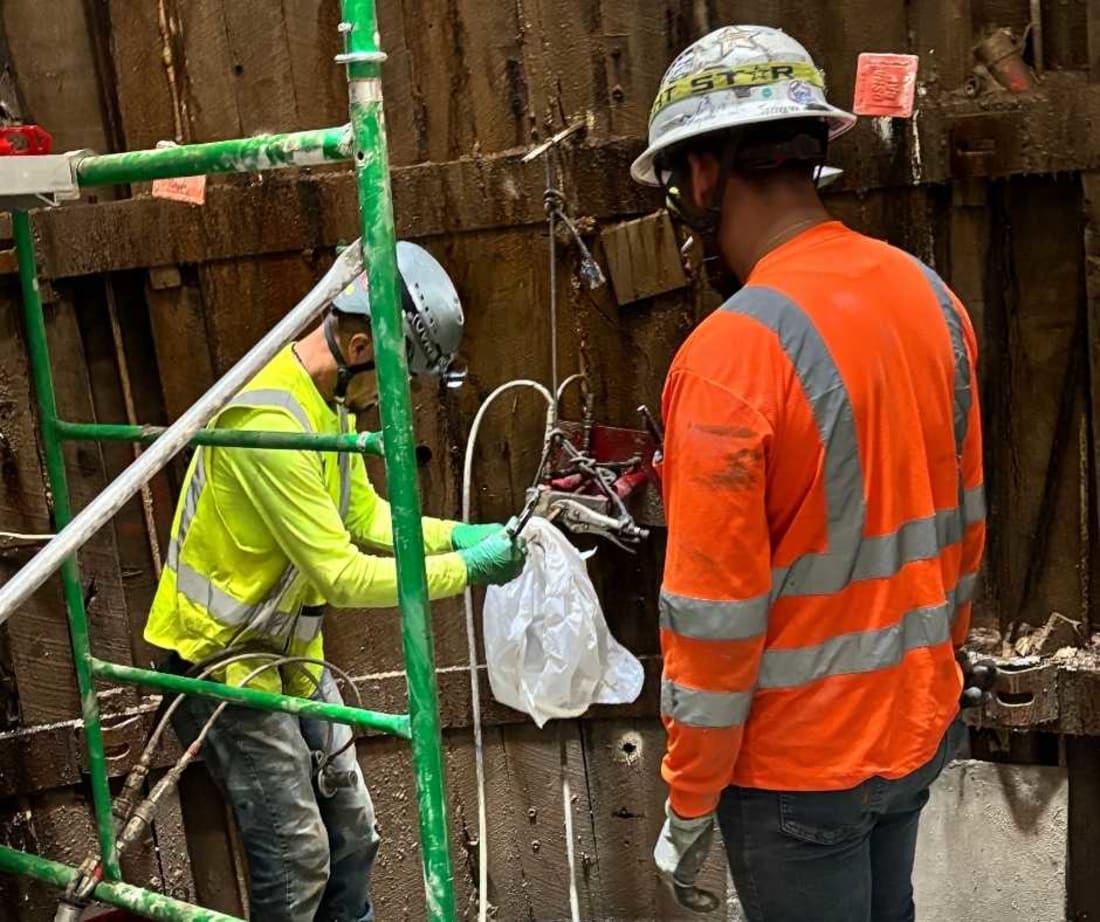 Image of Lincoln employees injecting NCFI geotechnical polyurethanes behind wood lagging to stabilize the soils