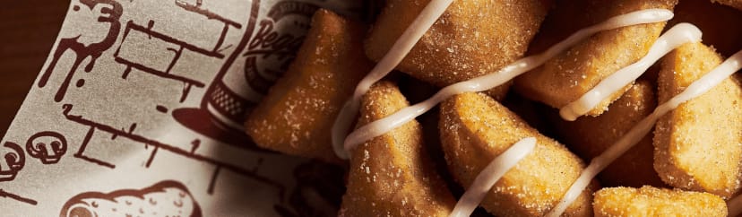 A close-up of Beggars Pizza sweet dough bites with an icing drizzle
