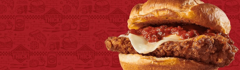 A close-up shot of a chicken sandwich topped with cheese and sauce on a toasted bun.