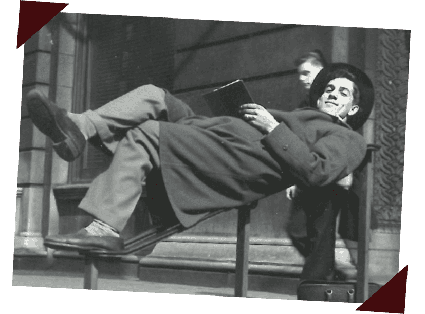 A young Angelo Garetto, founder of Beggars Pizza, sits atop the railing at the Art Institute of Chicago, smiling with a book.