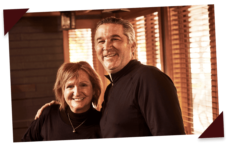 Two Beggars Pizza team members wearing black uniforms face the camera, smiling