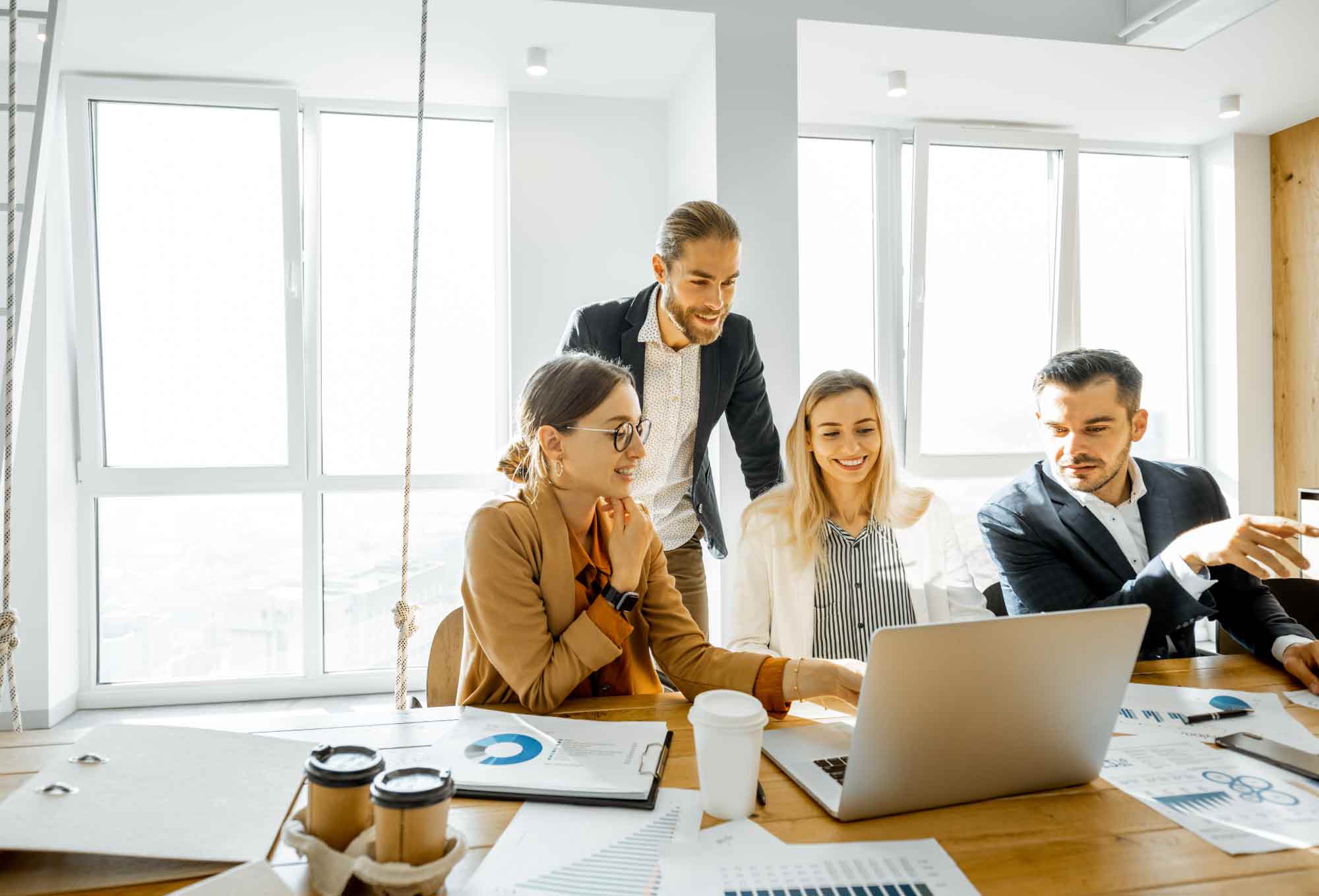 a group of people working on a laptop at a table in office