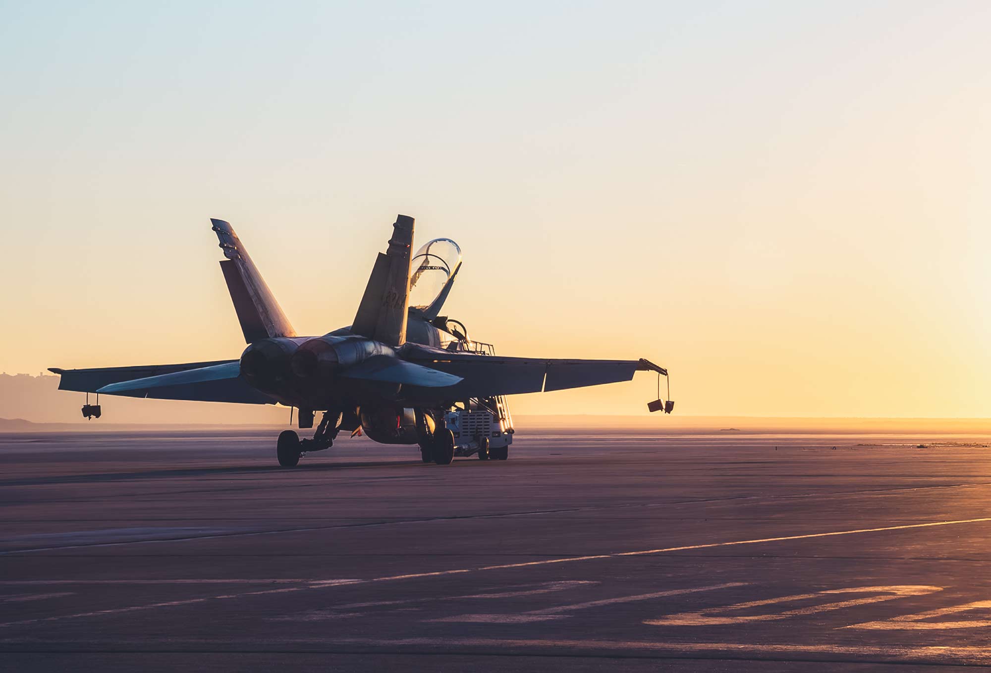 jet plane sitting on runway at sunset
