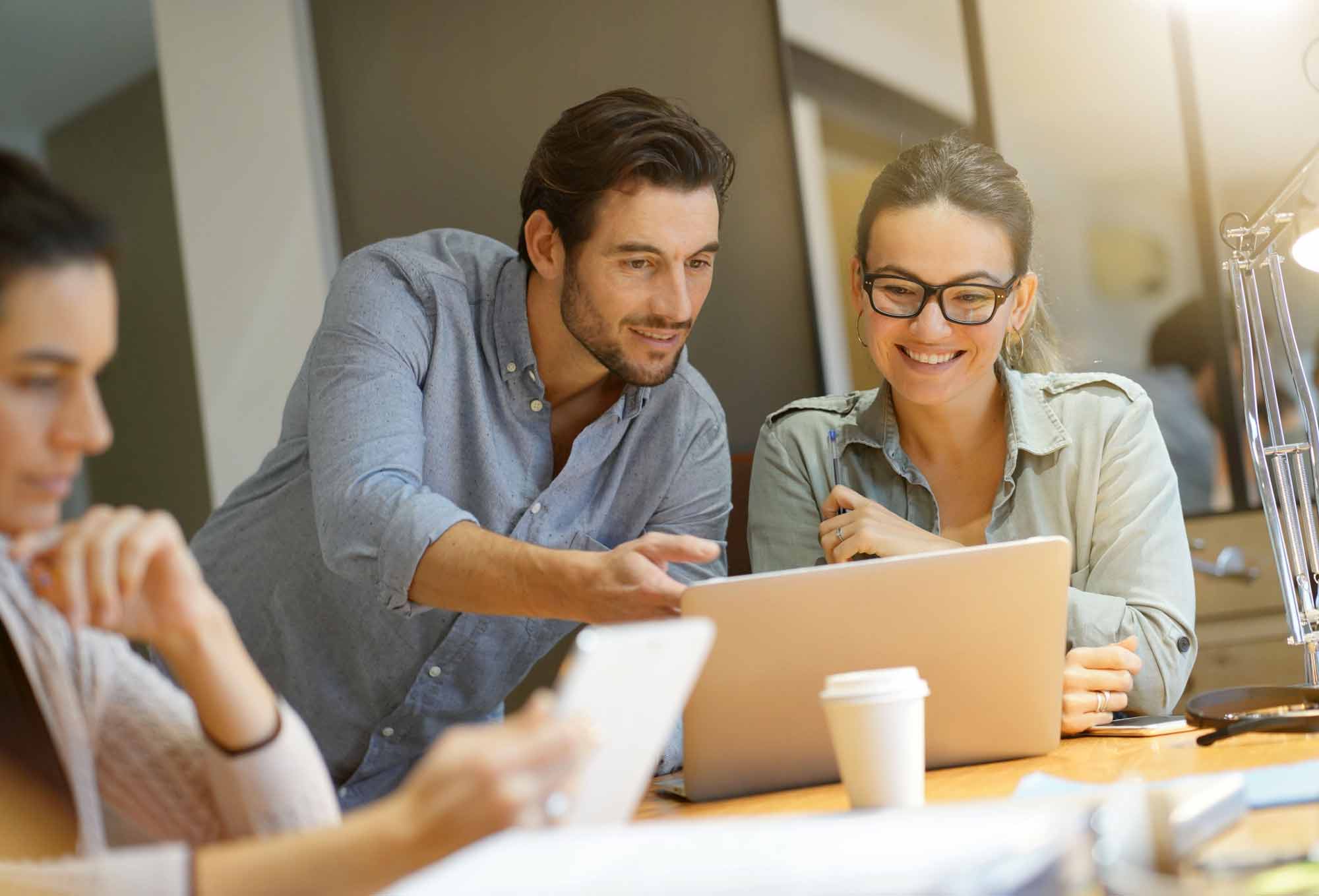 happy people working at table with laptop