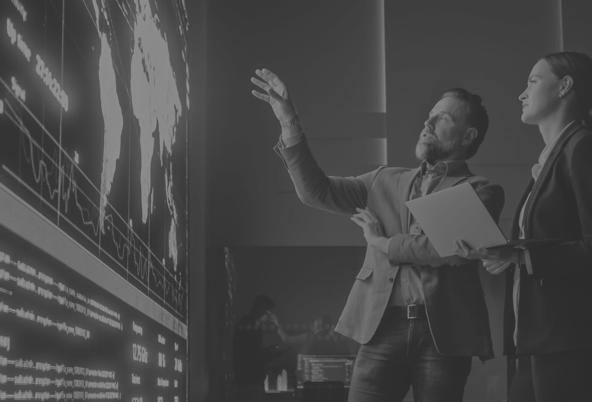 two men looking at a large screen showing data