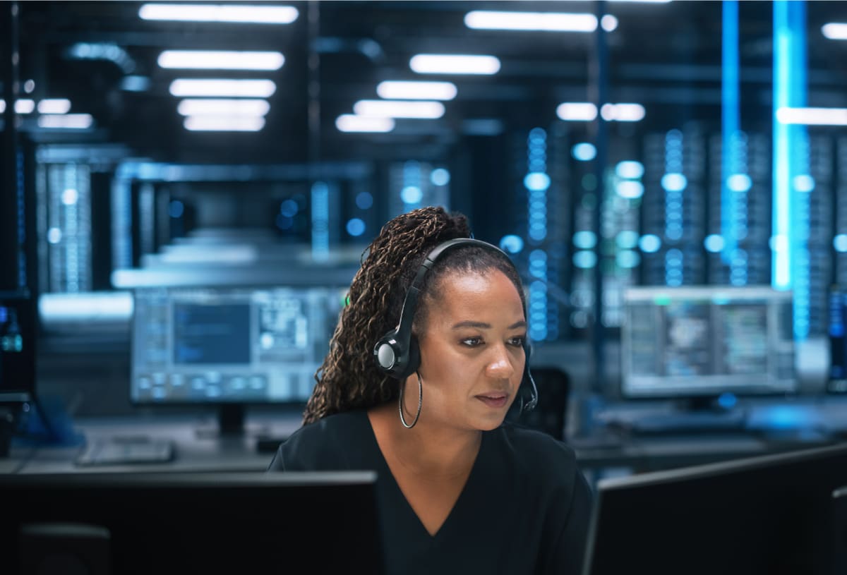 Woman in a room full of computers and other tech | Cloud Based Disaster Recovery Explained | Impact Networking