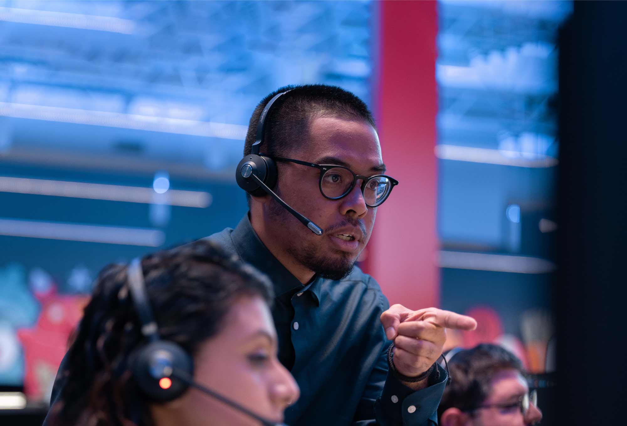 man with headset pointing at screen in security operations center