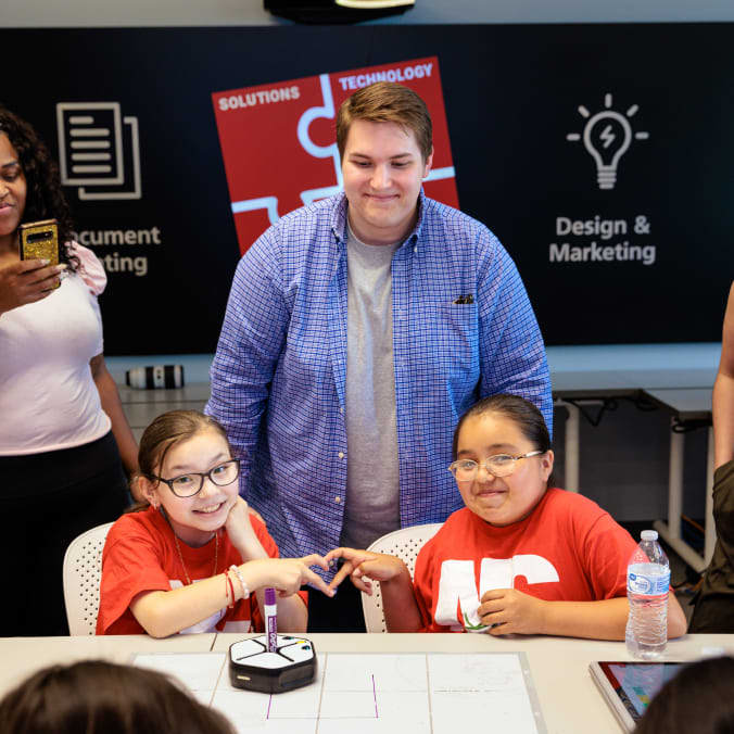 Two kids making a heart together with their hands wearing Impact U shirts