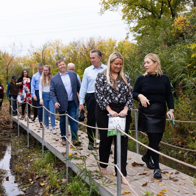 Group of impact team members walking through the new wetlands renovation bridge
