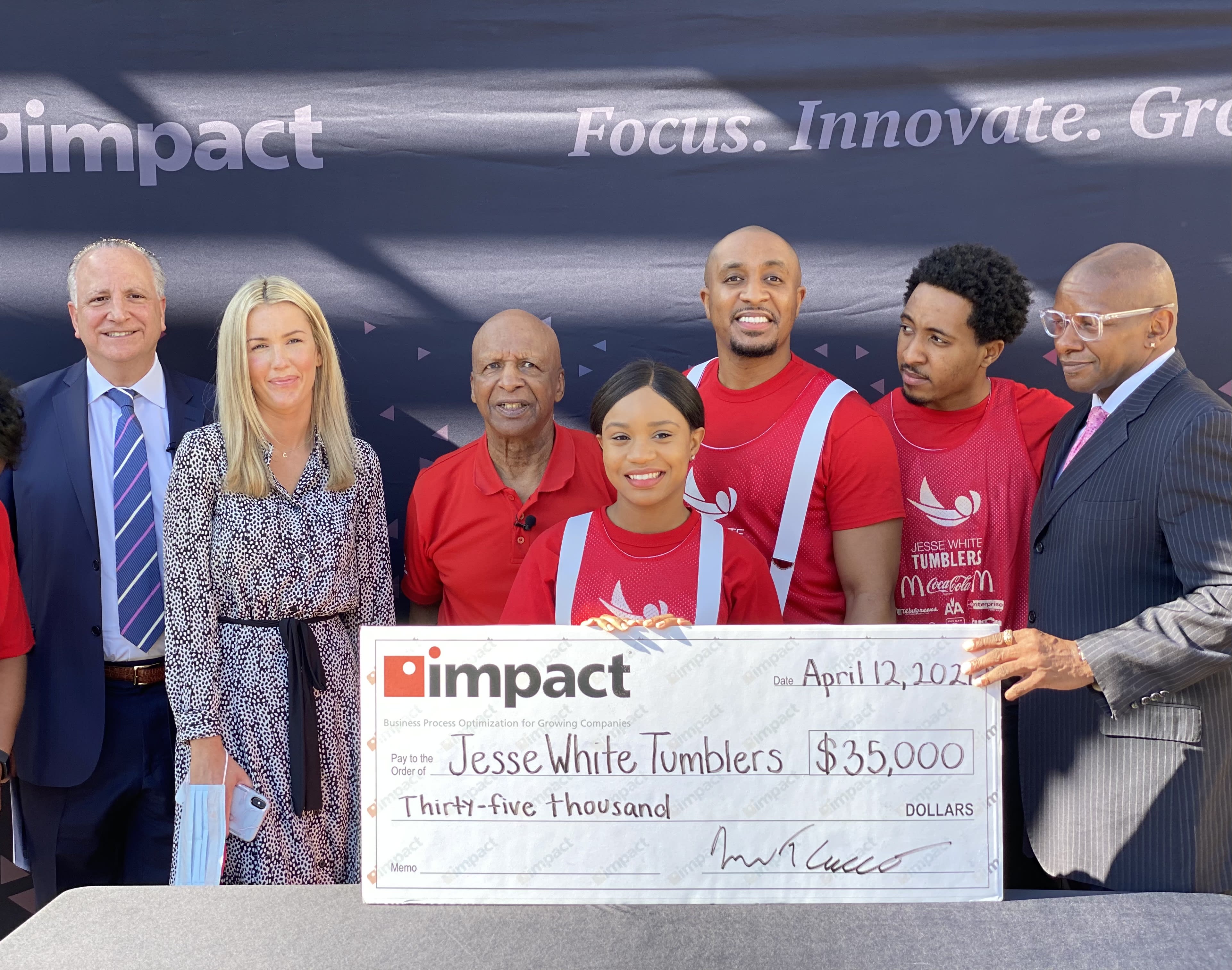 Impact Presents Illinois Secretary of State Jesse White and the Jesse White Tumblers with large donation check