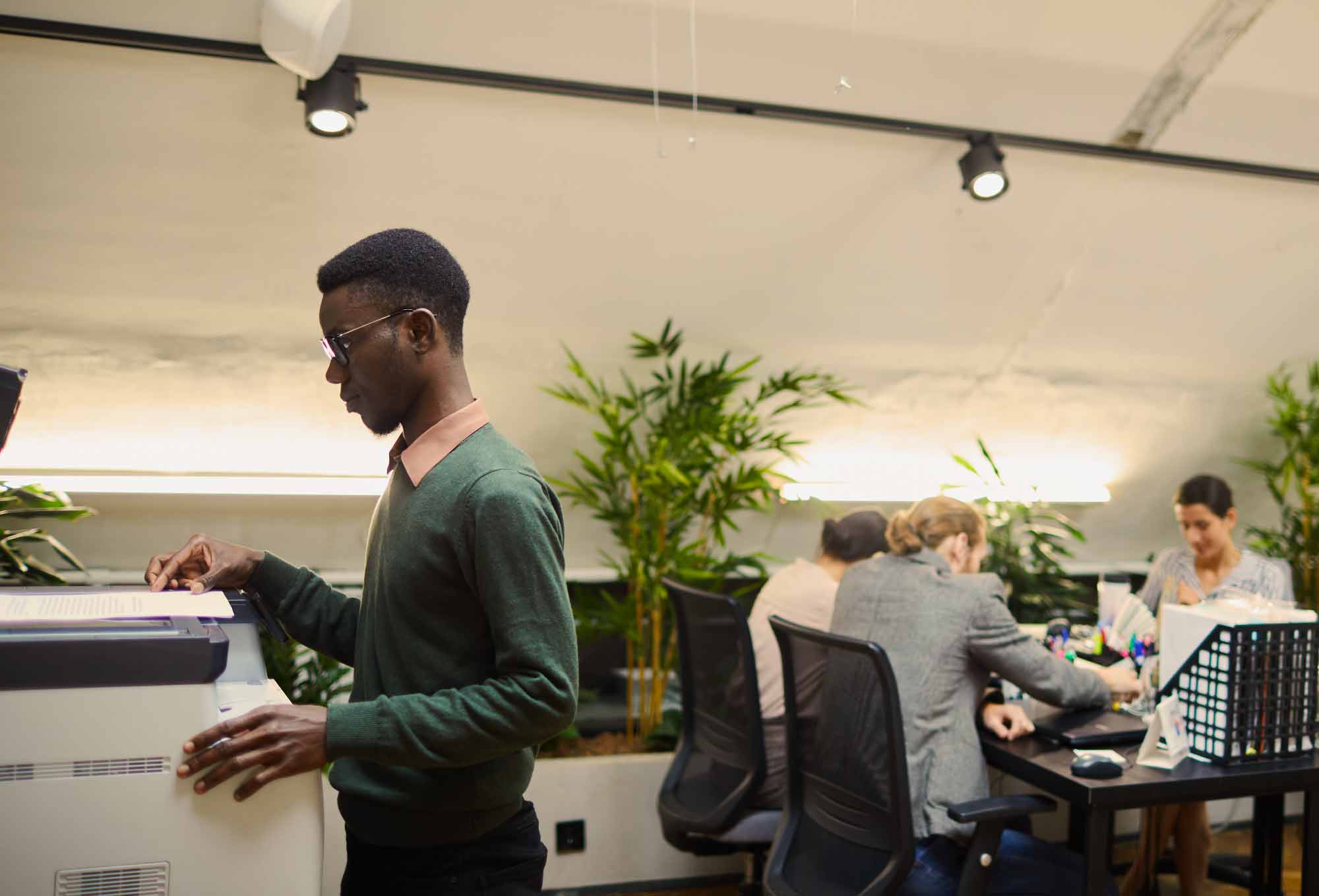 person standing next to a printer printing