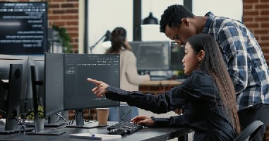 two people looking at a screen and one of them pointing