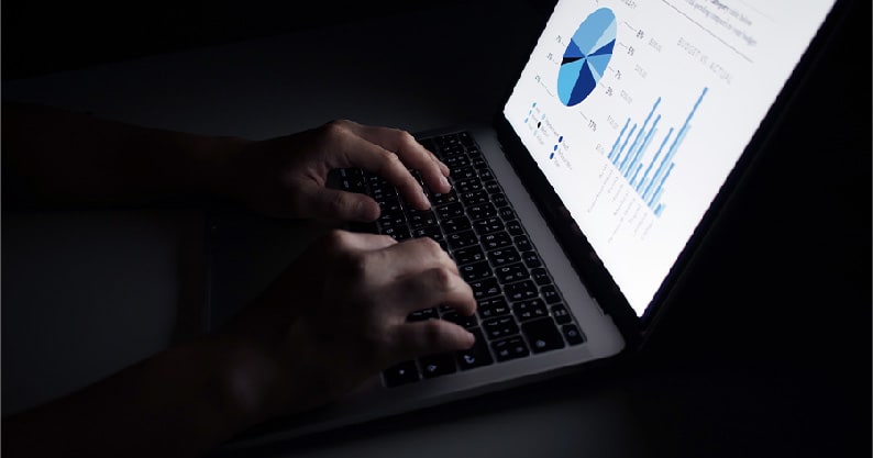 a person in the dark typing in a laptop