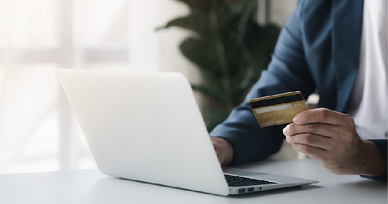 a person with their credit card and laptop