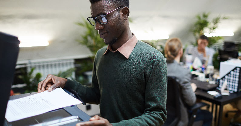 man putting a piece of paper into a scanner