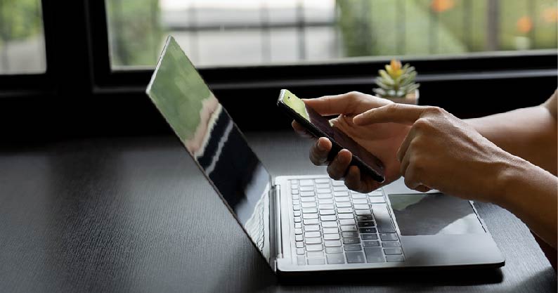 a person using a phone and laptop